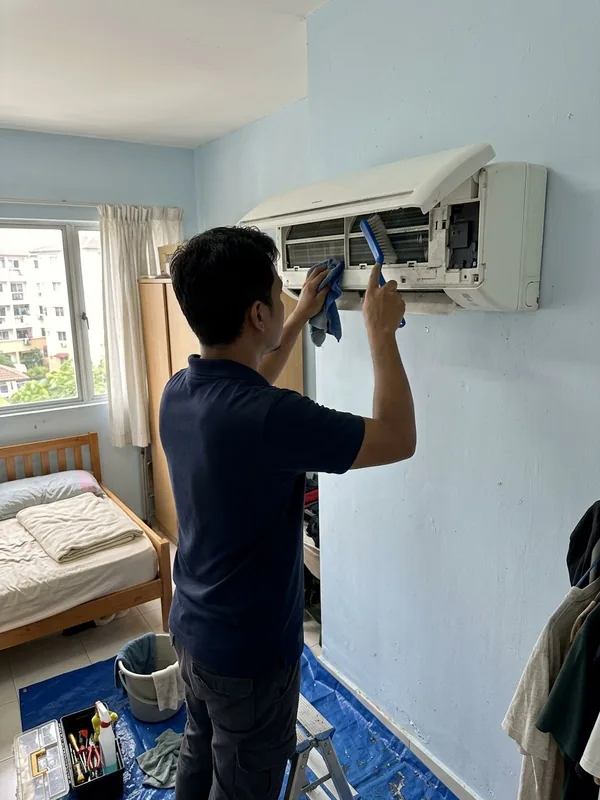 Technician mencuci aircond di dalam bilik
